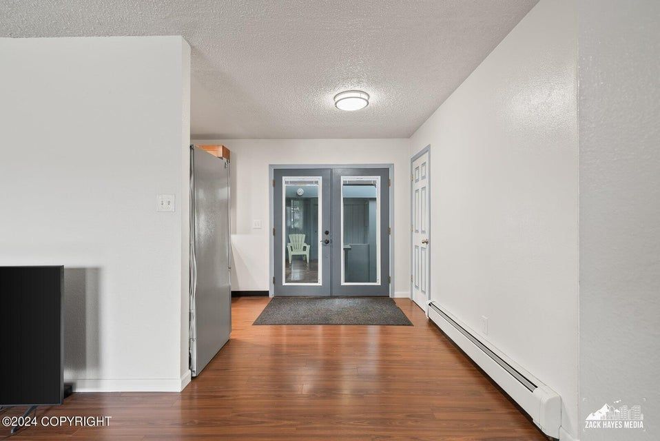 Hallway with wood floors, white walls, gray doors, and overhead lighting.