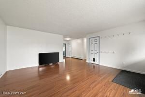 Empty living room with wood flooring, white walls, and a mounted TV.