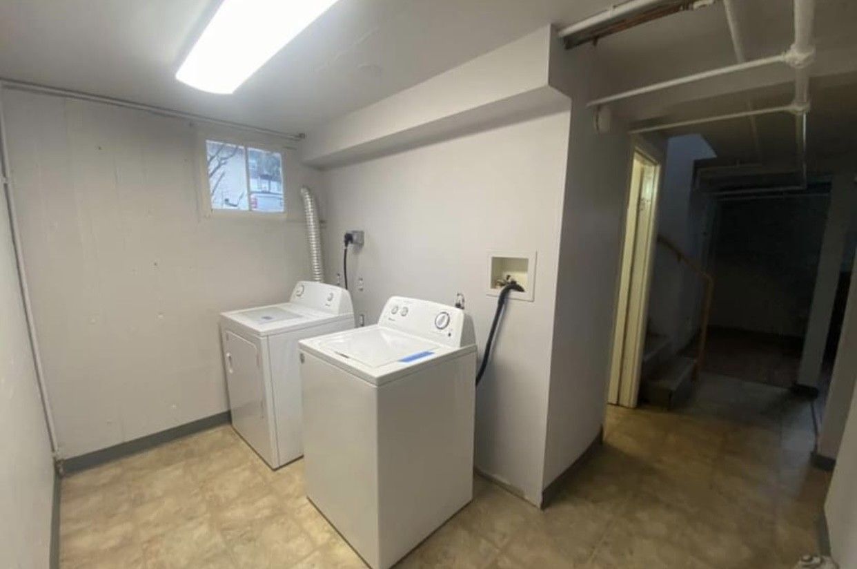 Laundry room with white washer and dryer, small window, and doorway to the right.