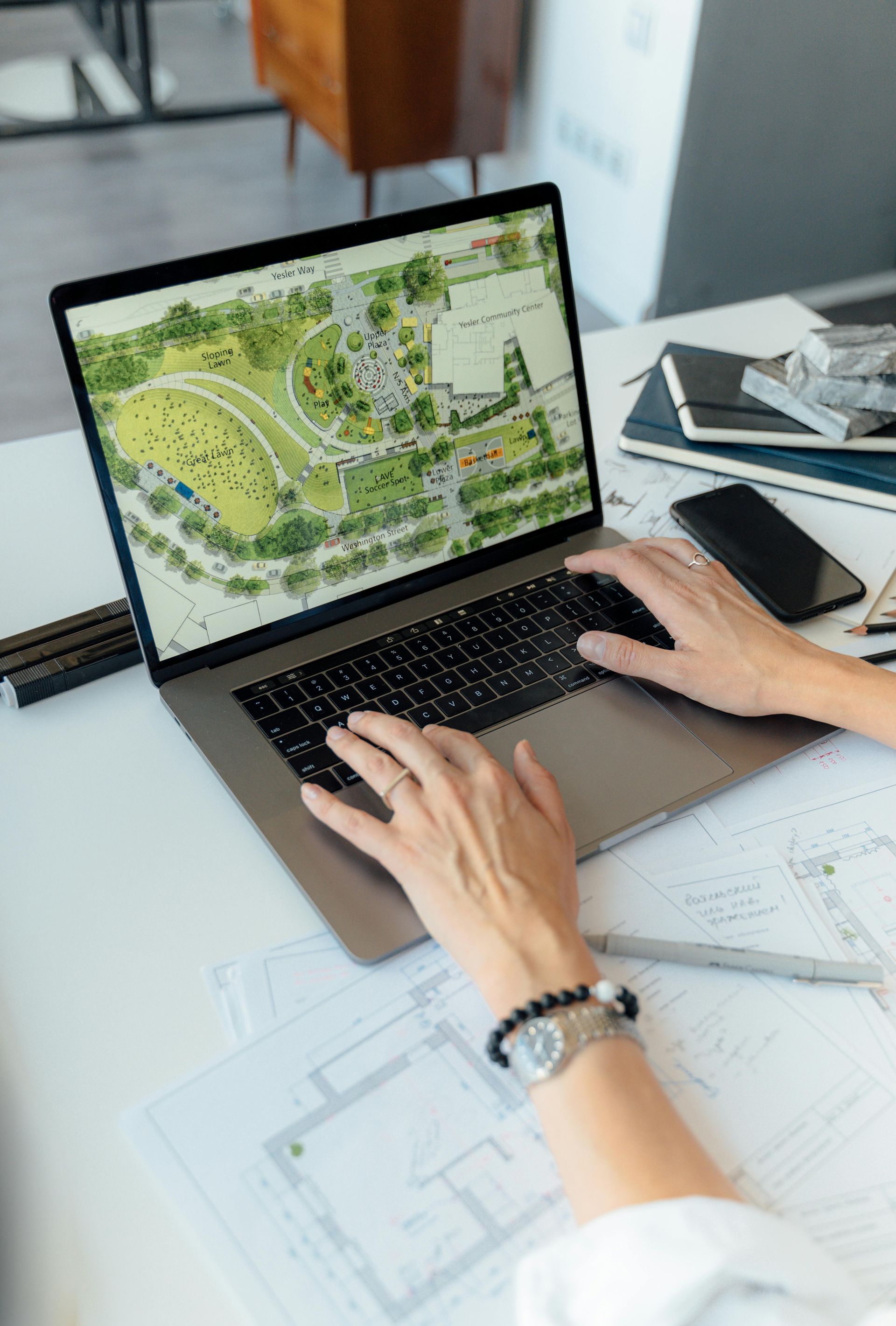 A person is typing on a laptop computer with a map on the screen.