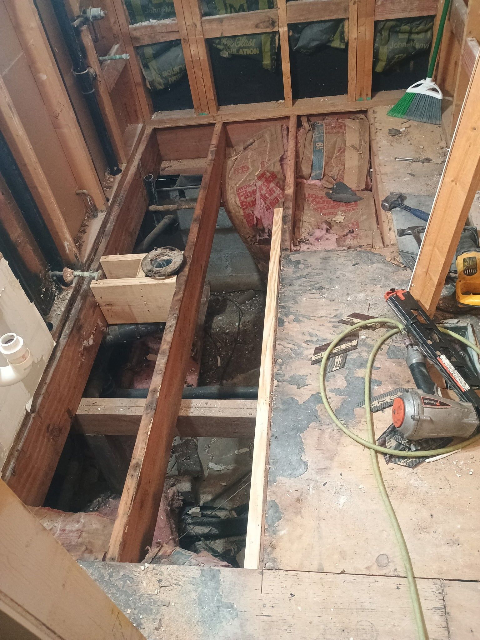 Renovation site with exposed floor joists, open floor cavity, and tools scattered on the subfloor.