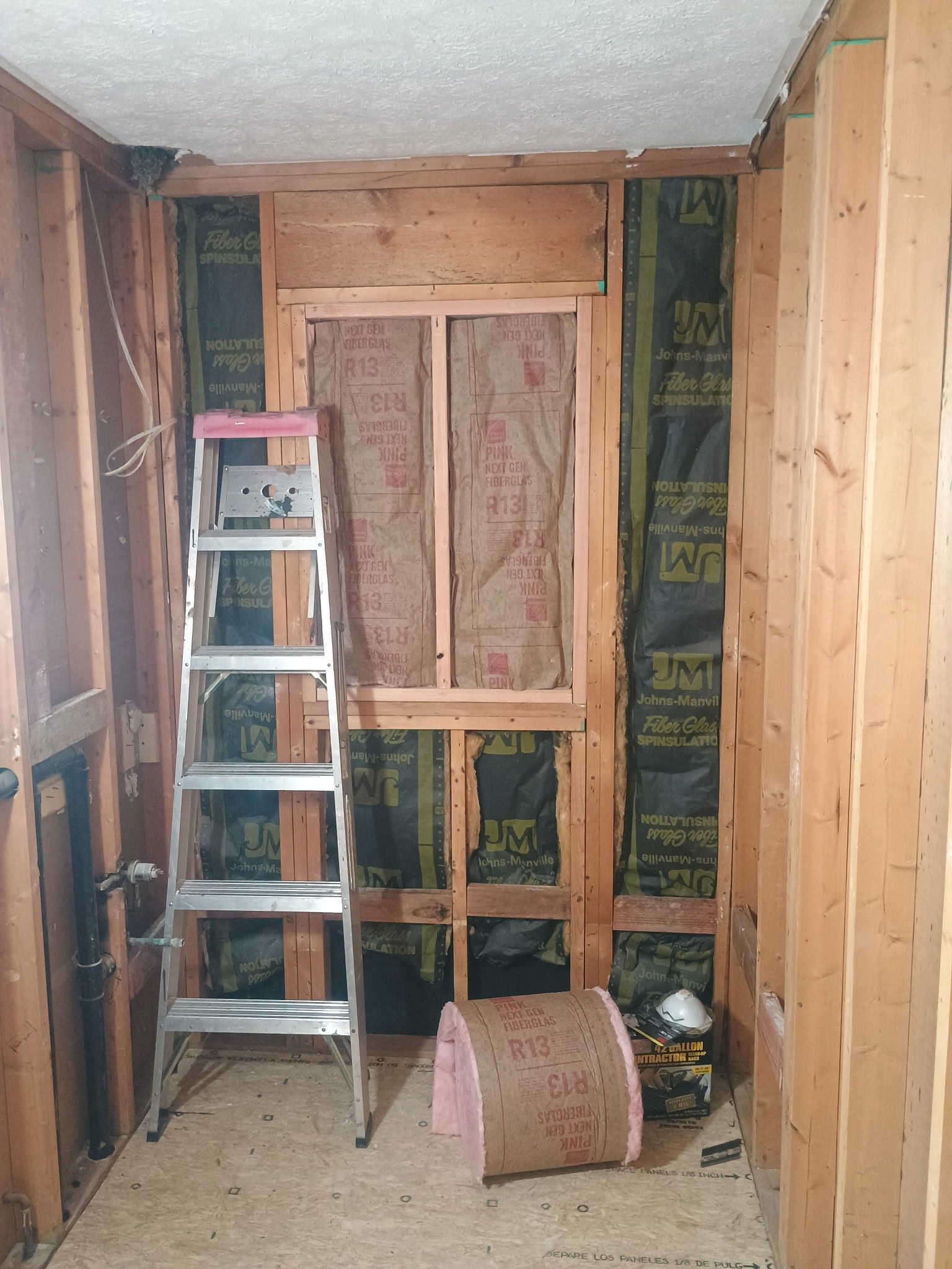 Unfinished room with exposed studs, a ladder, and insulation during renovation
