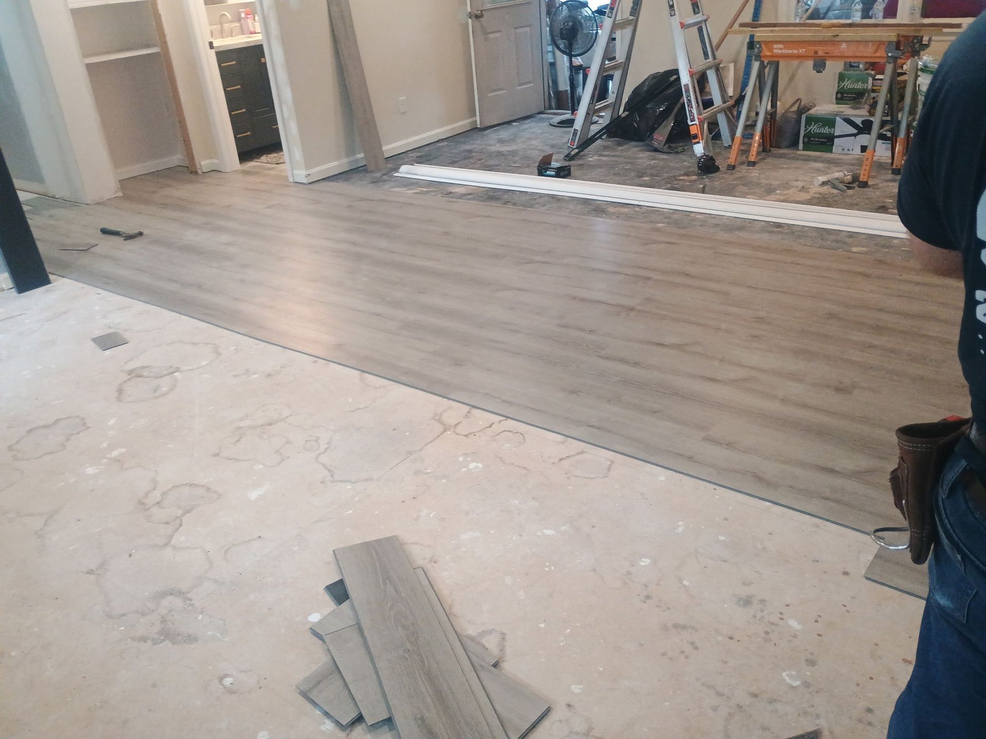 Partially installed wood flooring in a room under renovation, with tools and debris visible.