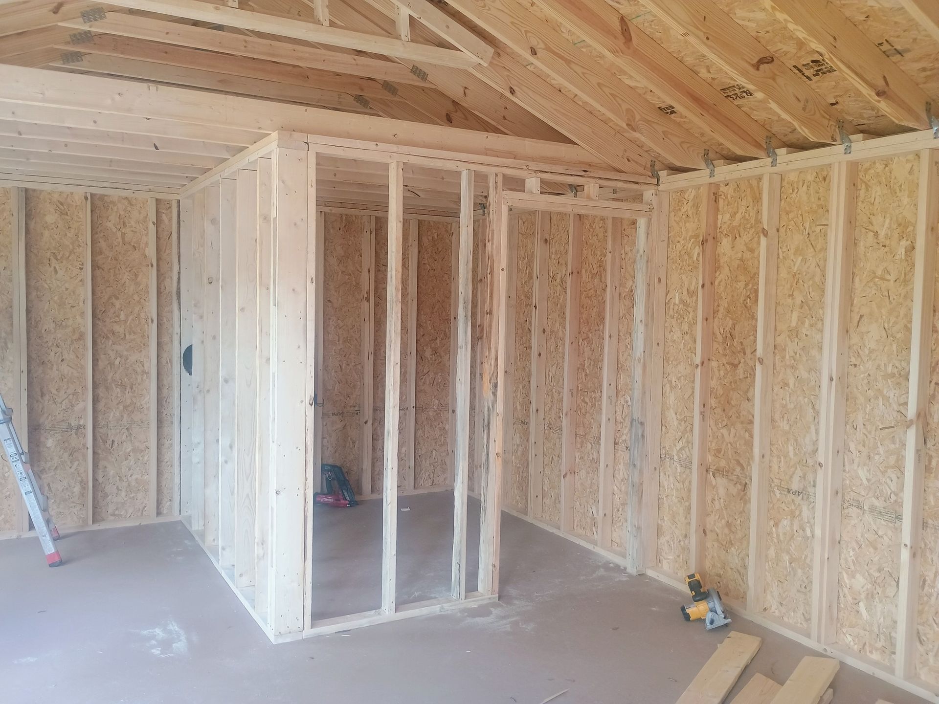Unfinished framed interior of a house with exposed wood studs and ceiling beams