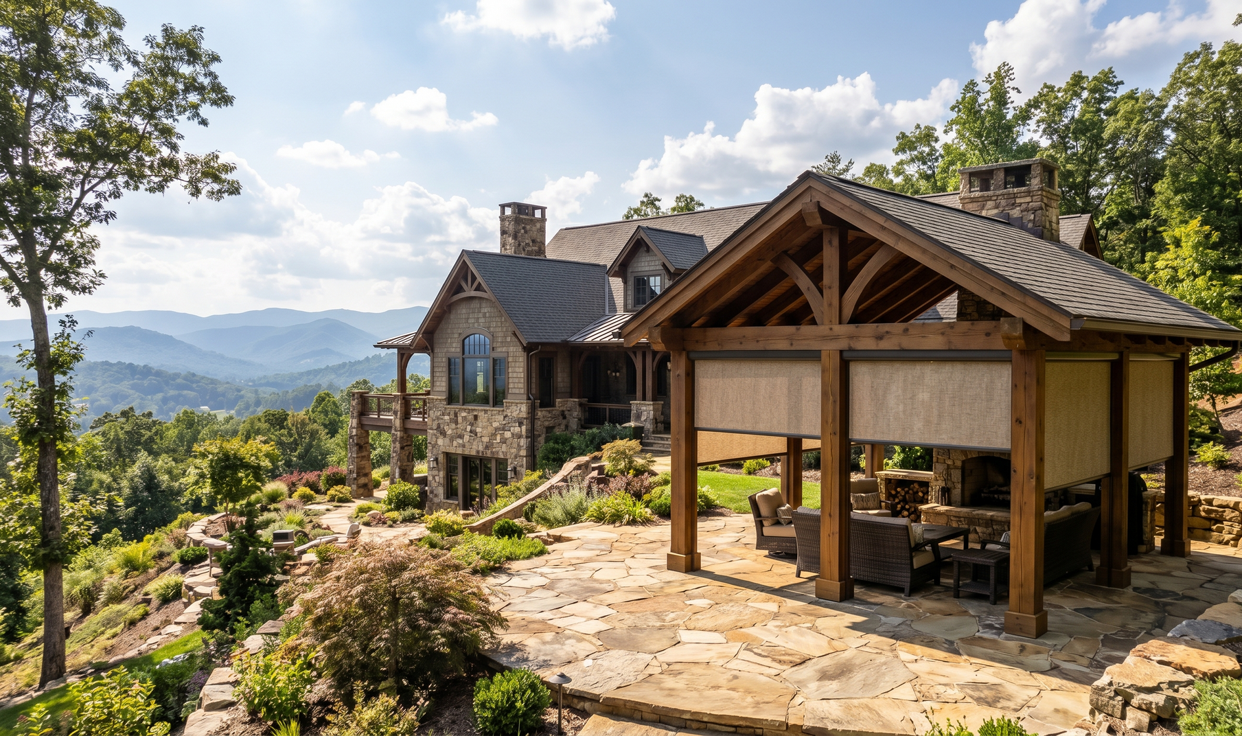 Mountain lodge with stone patio and wooden pavilion overlooking a scenic valley and distant hills
