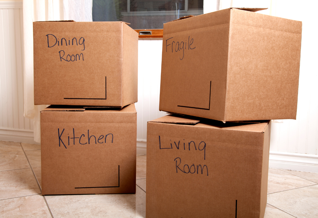 A stack of boxes labeled for different rooms in a home.
