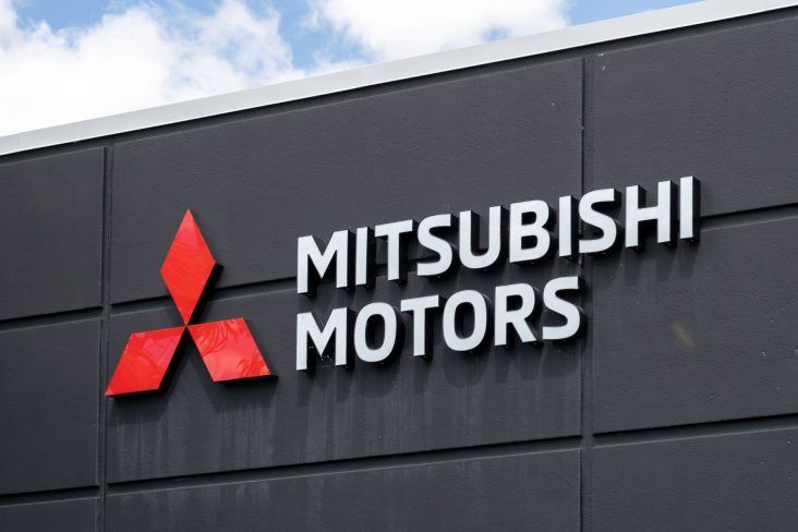 Placa da Mitsubishi Motors em um prédio cinza escuro. O logotipo é vermelho e branco.