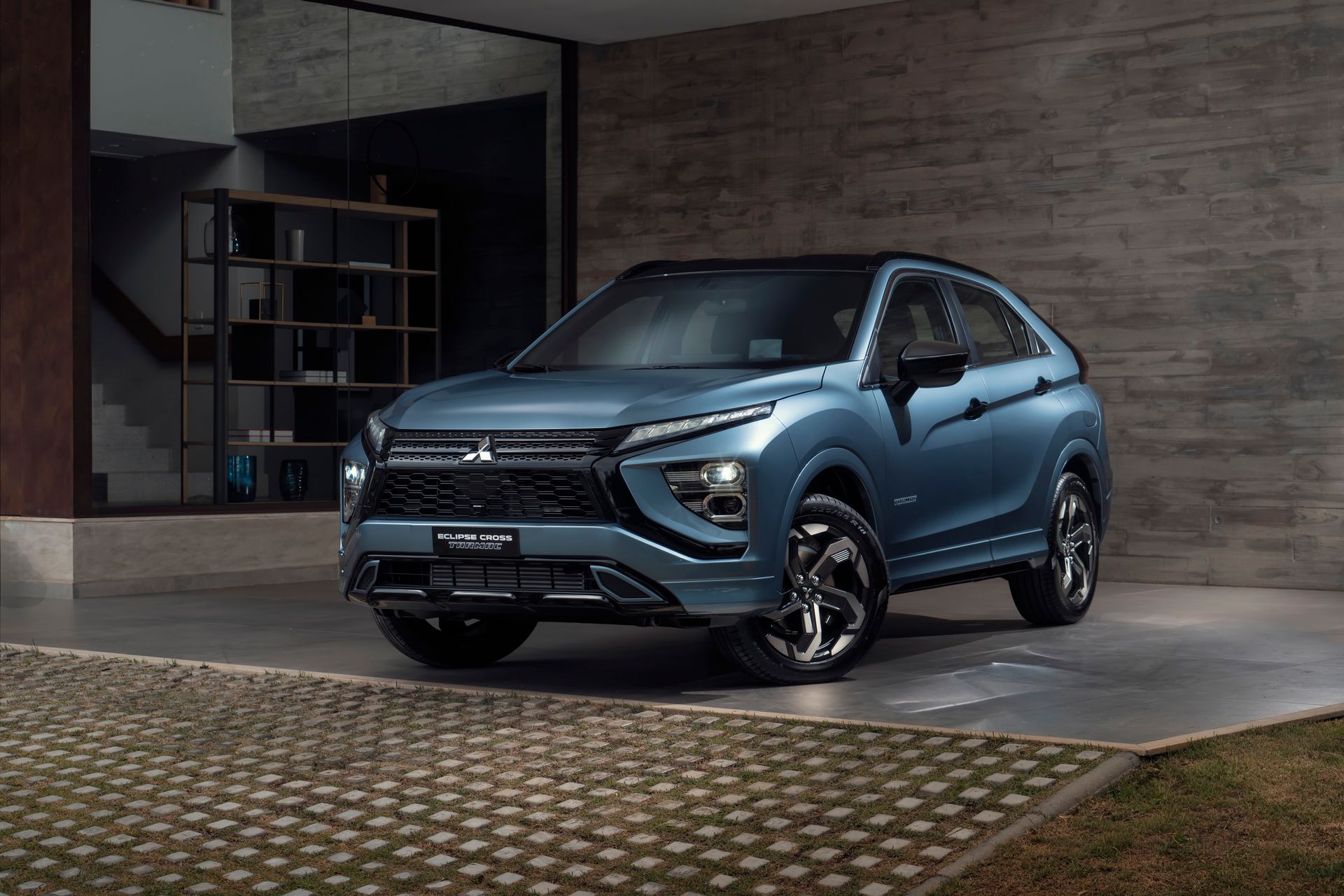 SUV Mitsubishi Eclipse Cross azul estacionado em frente a uma casa moderna.