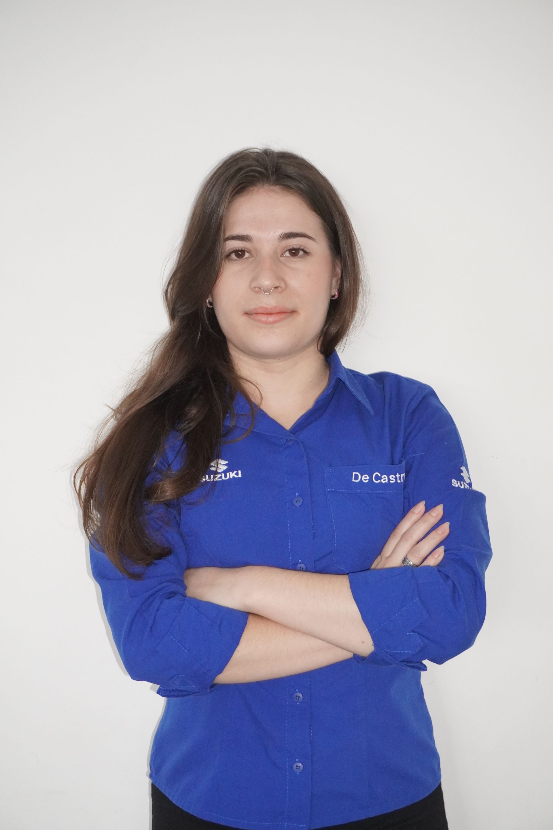 Mulher de camisa azul com os braços cruzados, sorrindo. Fundo branco.