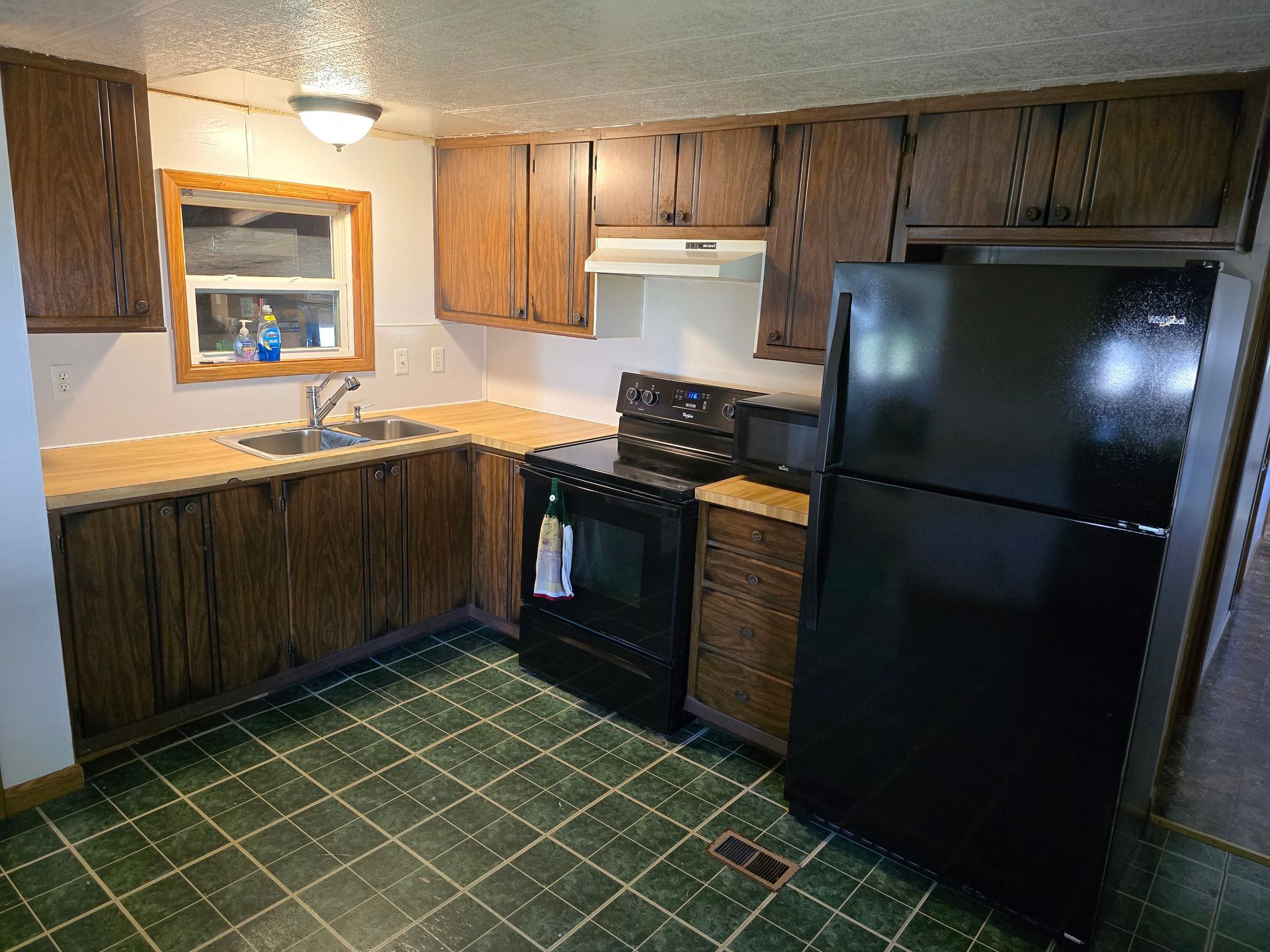 A kitchen with a black refrigerator stove and sink