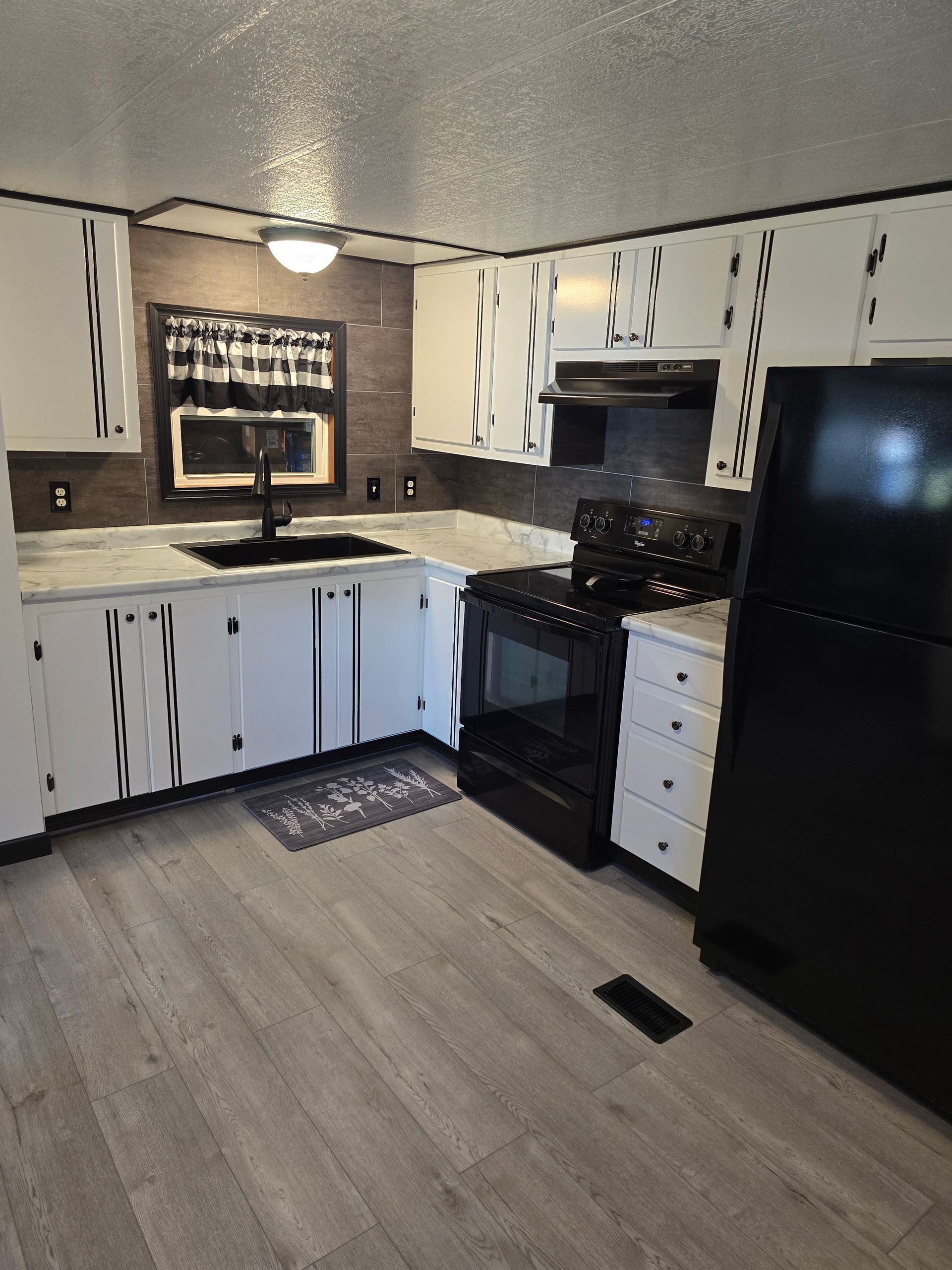A kitchen with white cabinets and a black refrigerator