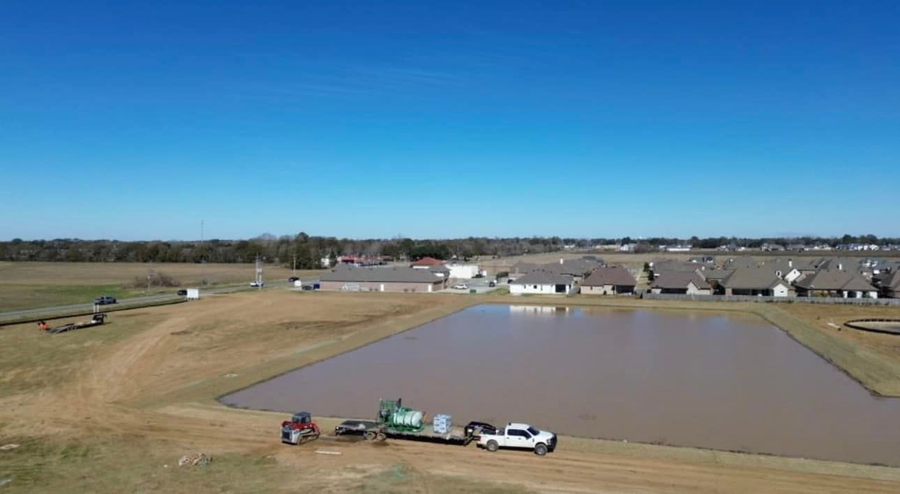 Flooded field with parked vehicles and farm equipment under a clear blue sky