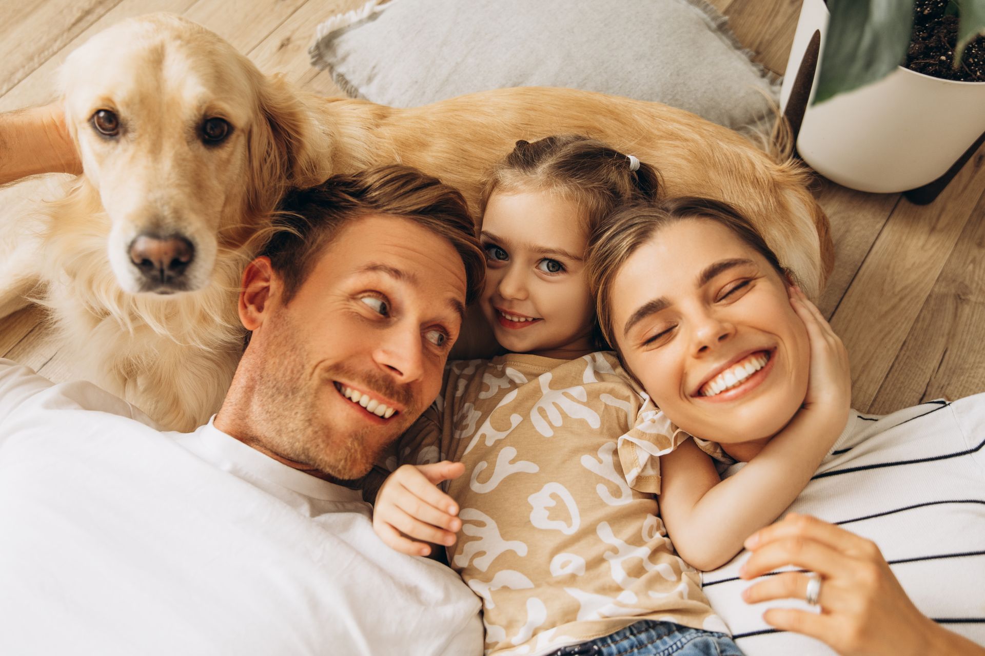 Family smiling on a couch with a golden retriever resting beside them