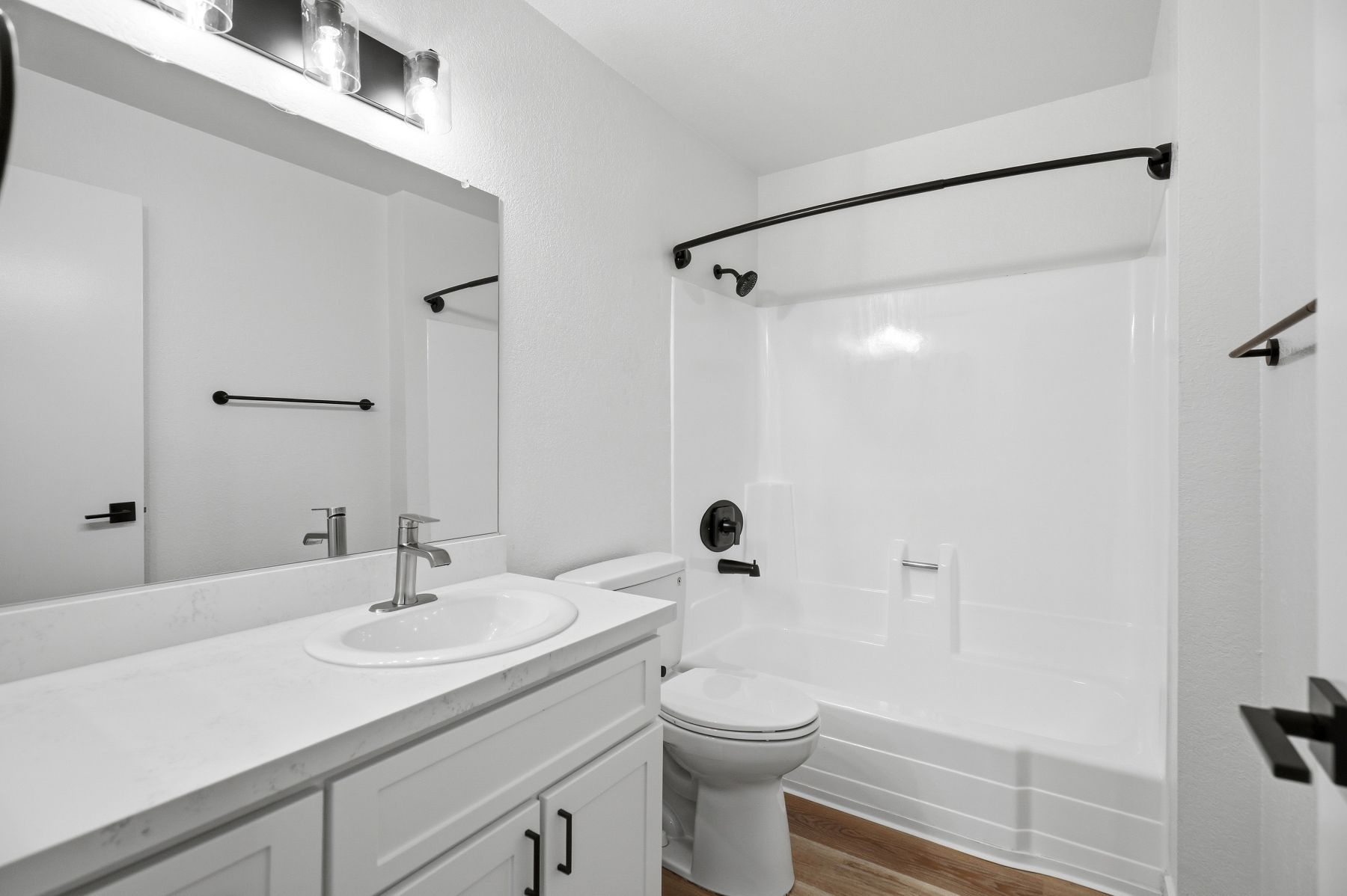 Modern white bathroom with vanity, sink, mirror, toilet, and shower curtain
