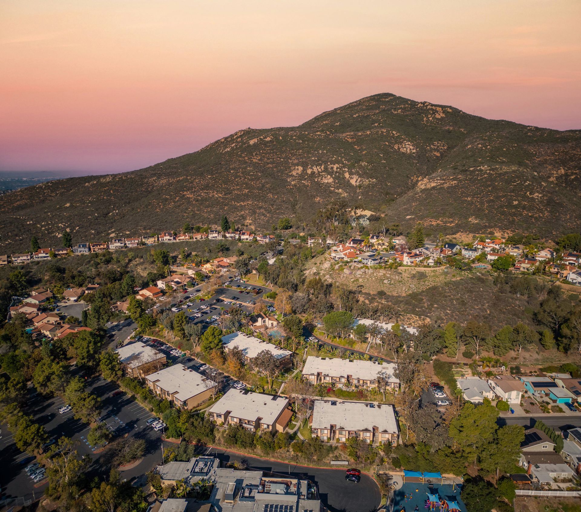 Aerial view of a hillside resort neighborhood with palm trees at sunset