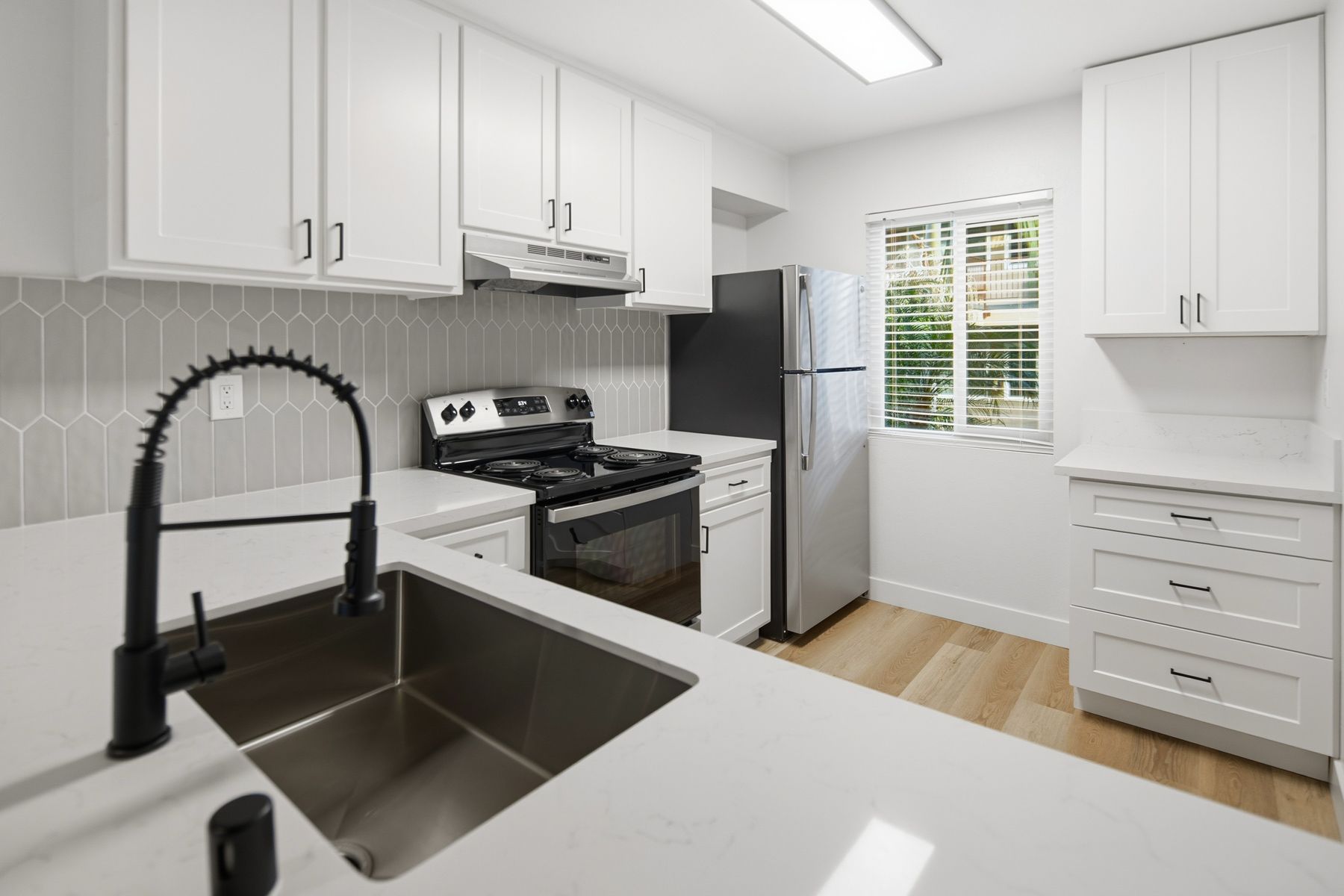 Kitchen with brown cabinets, white appliances, and light countertops and flooring at Cowles Landing in San Diego, CA.