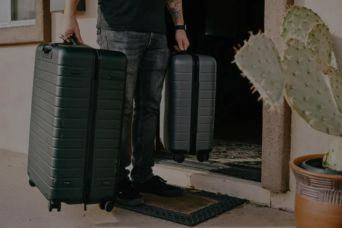 Un hombre lleva dos maletas a una casa.
