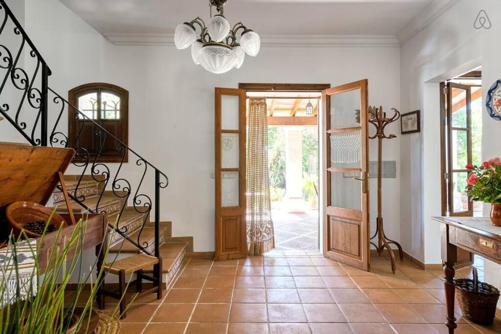 Entrada de azulejos con puertas de madera que dan a un patio soleado. 