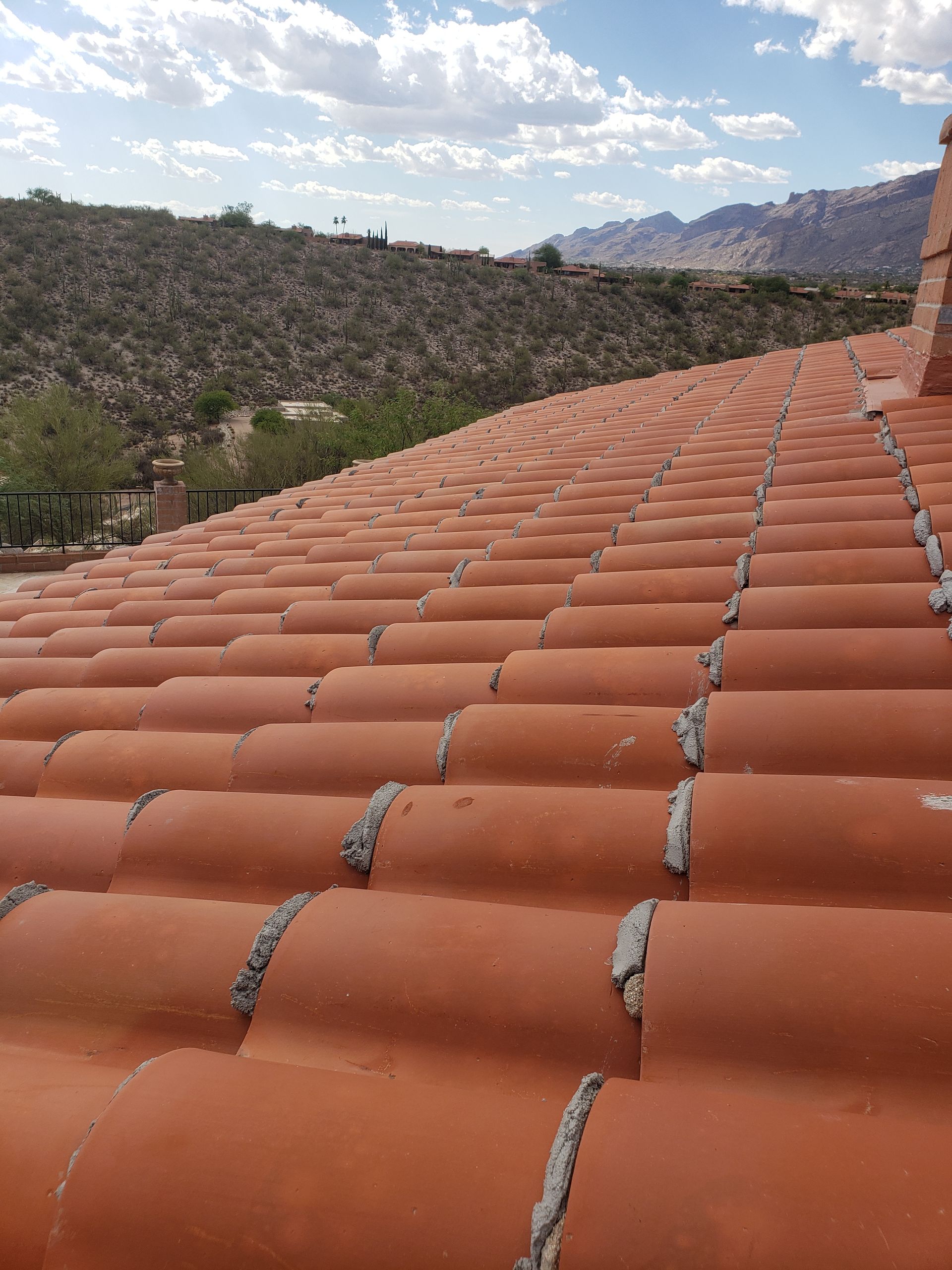 Terracotta tiled roof overlooking trees and distant mountains under a partly cloudy sky