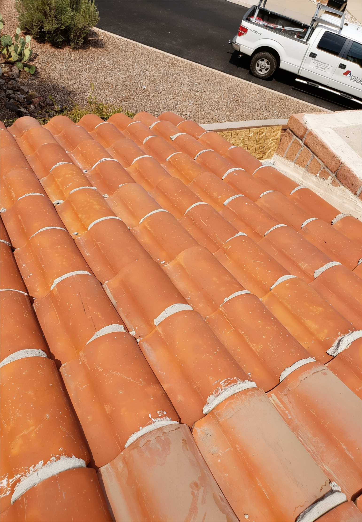 Terracotta roof tiles viewed from above, with a street and white truck in the background