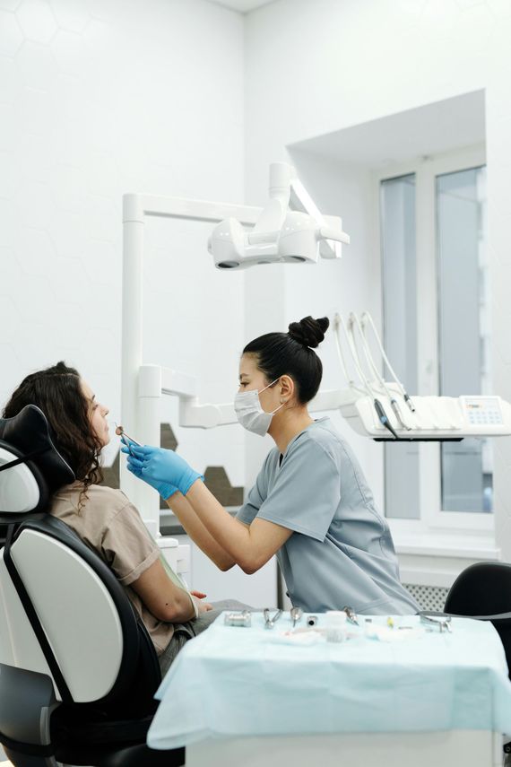 Dentist examining a masked patient in a bright clinic, with dental tools and chair nearby