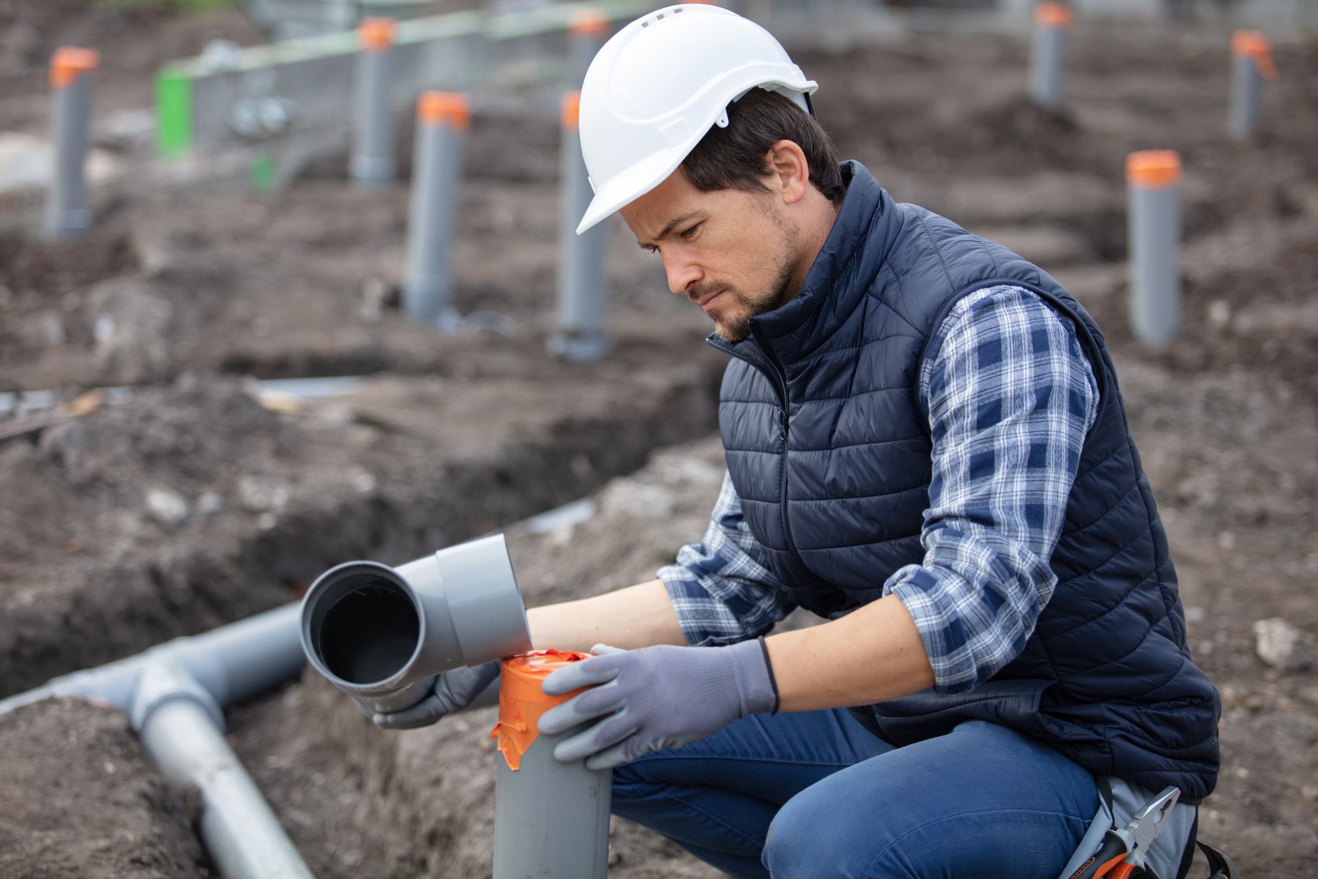 A plumber fixing sewerage pipe at a construction site