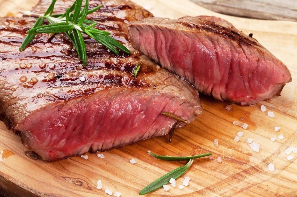 Due bistecche vengono tagliate a metà su un tagliere di legno.