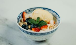 Una ciotola di gelato con fragole, mirtilli su un tavolo.