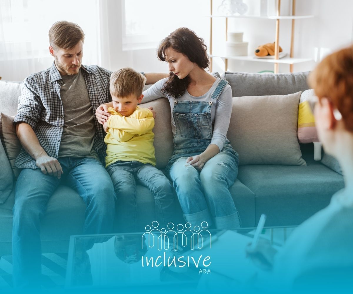 Family sitting on a couch with a toddler, in a bright living room with an