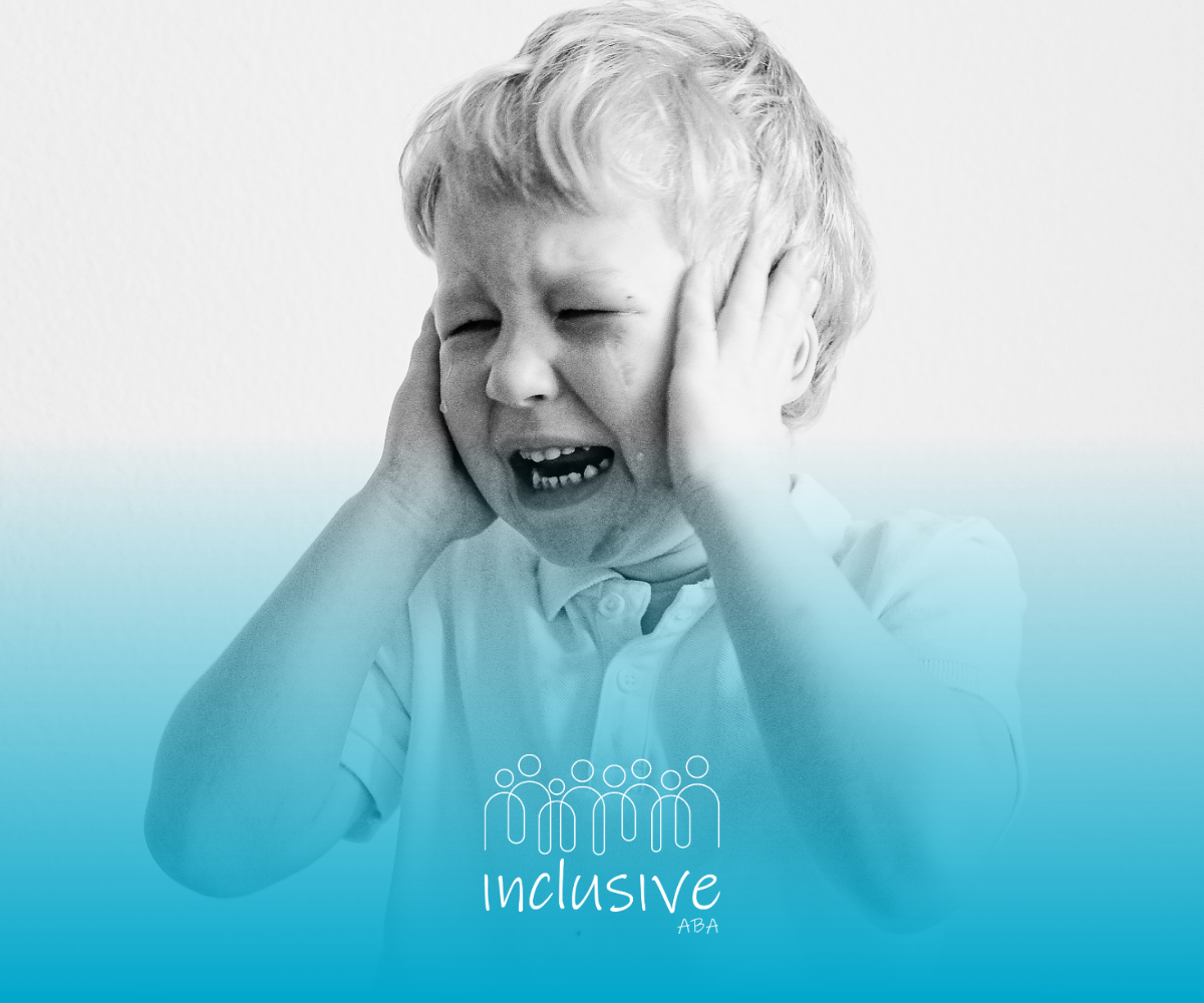 Young child covering ears and crying against a plain background