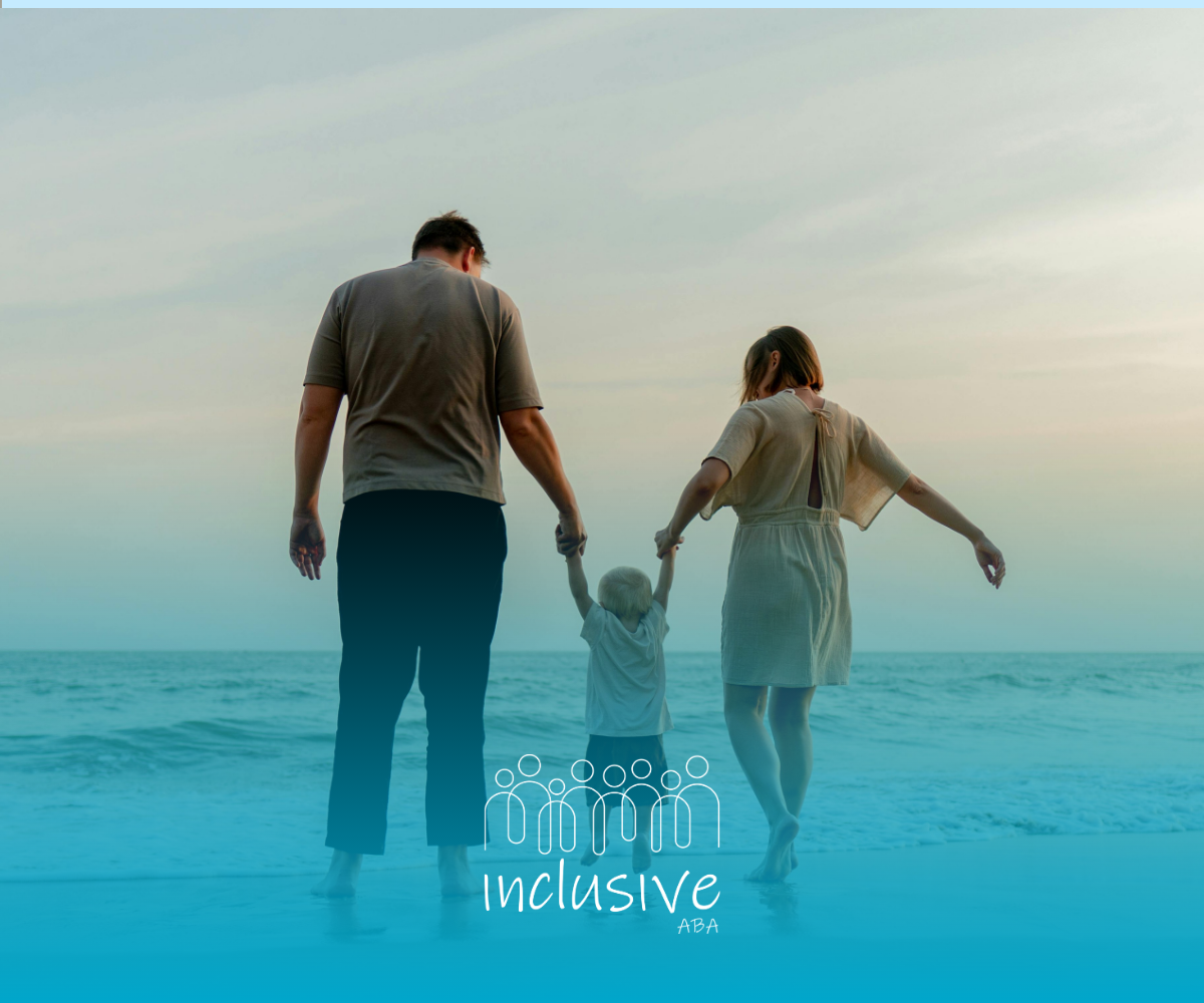 Family of three holding hands, walking along a beach at sunset.