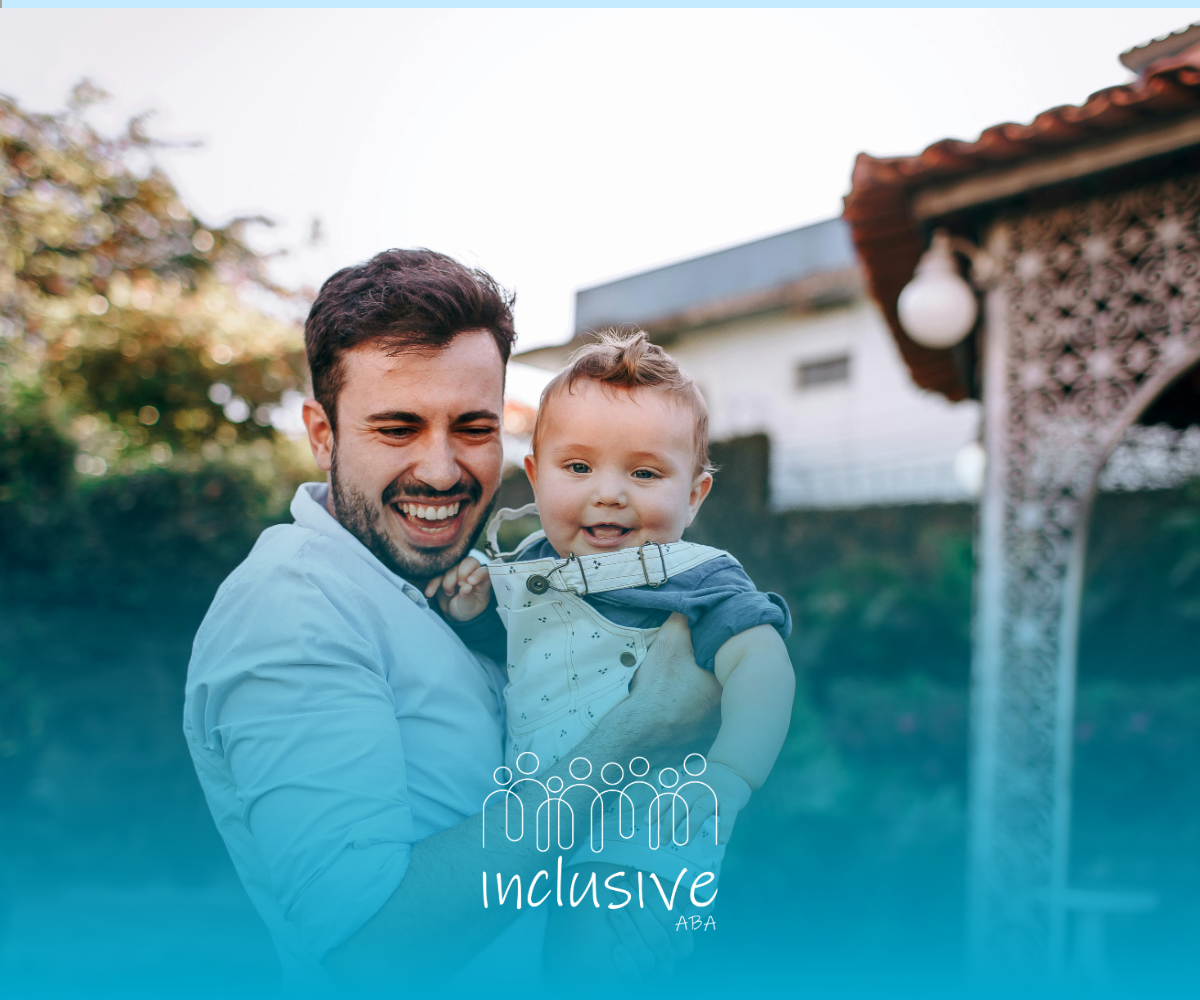Smiling man holding a baby outdoors, with a turquoise overlay at the bottom.