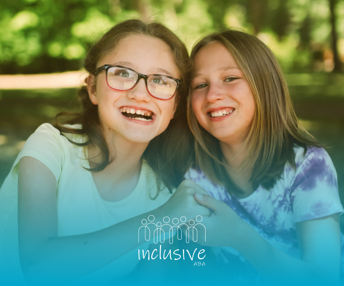 Two smiling children sitting together outdoors on a sunny day.