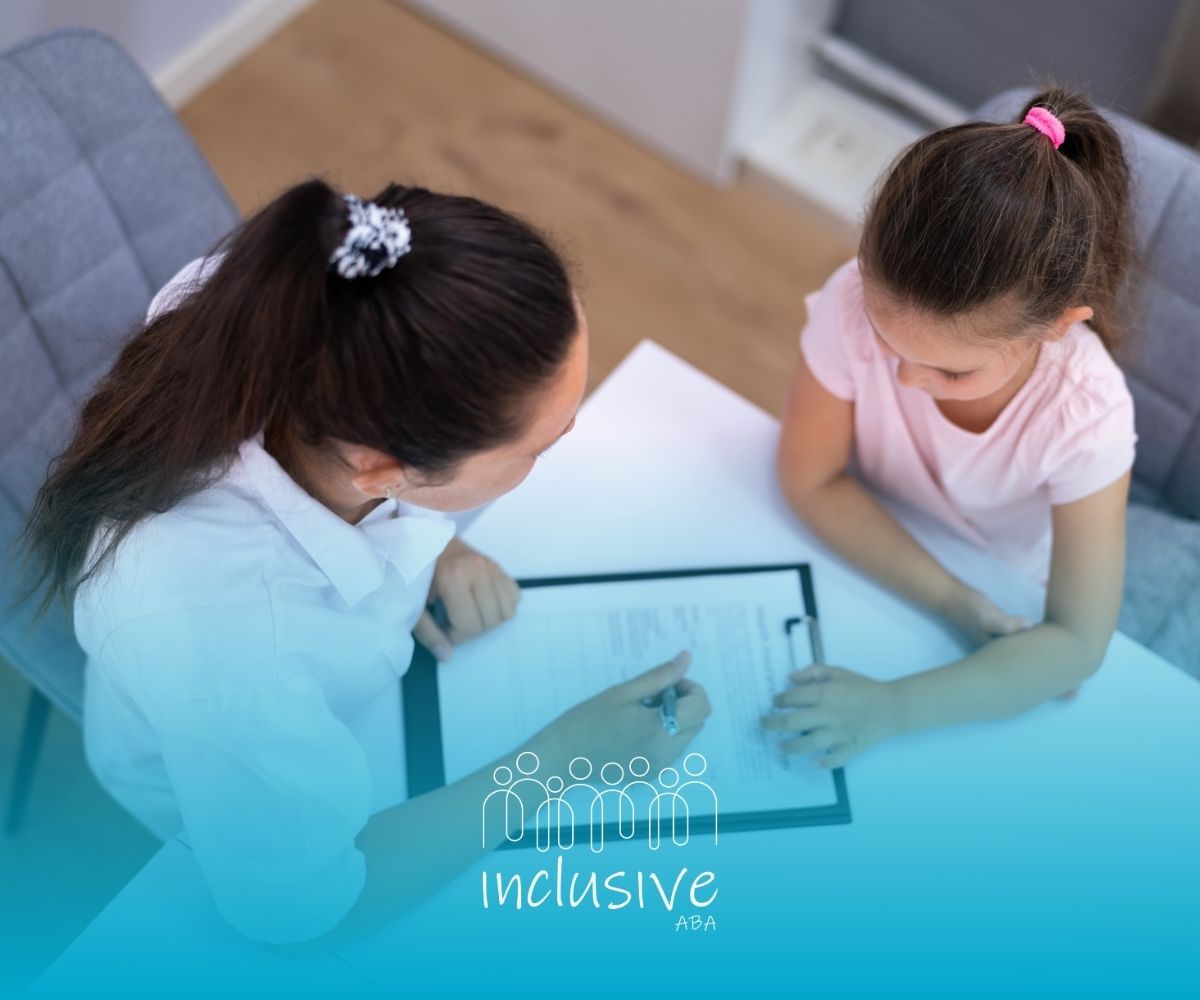 Two children lean over a table, pointing at a worksheet in a bright classroom.