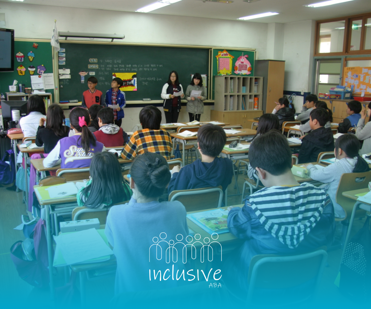 Students seated in a classroom watch a presentation at the front of the room.