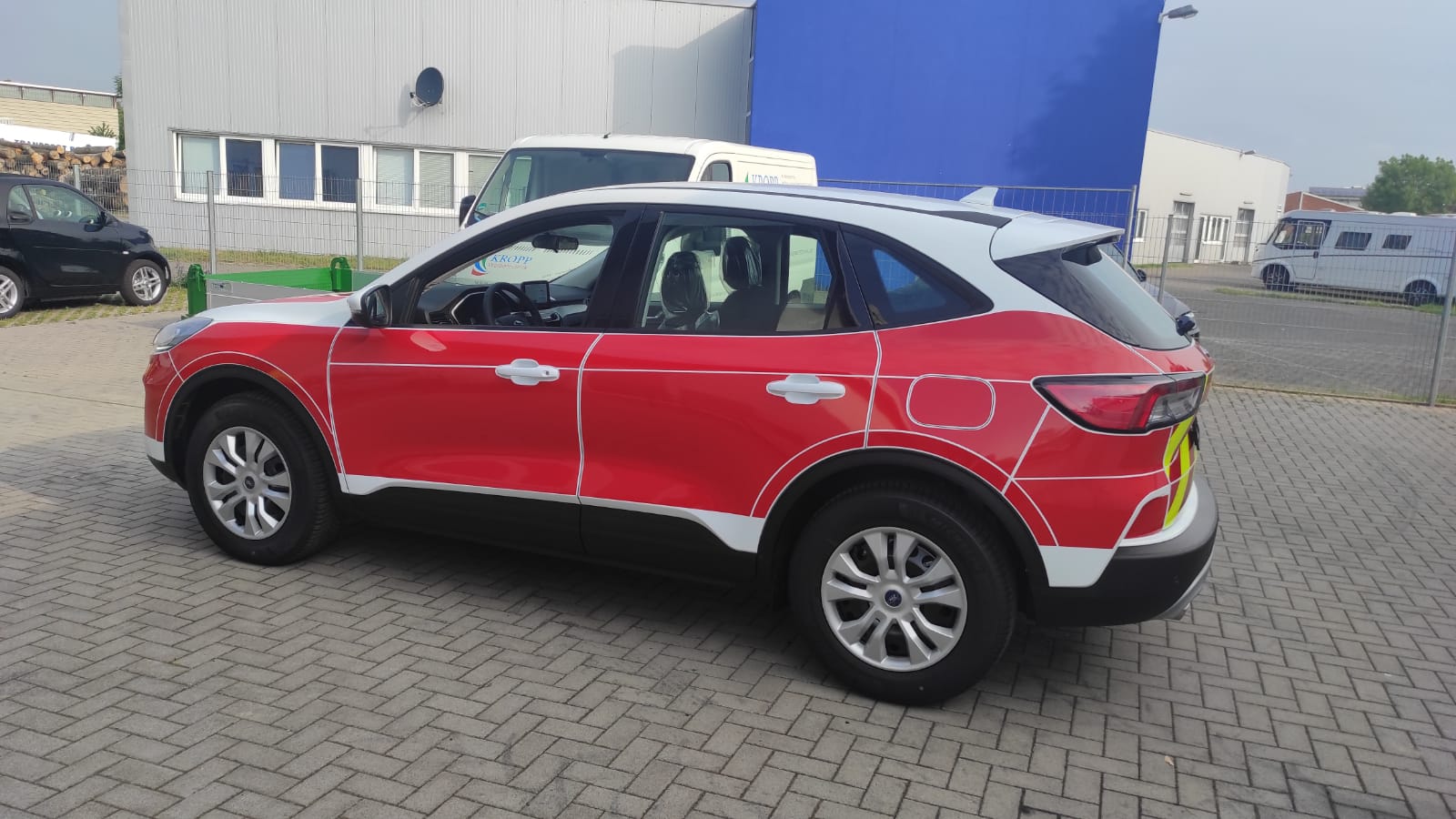A red and white car is parked in front of a building.
