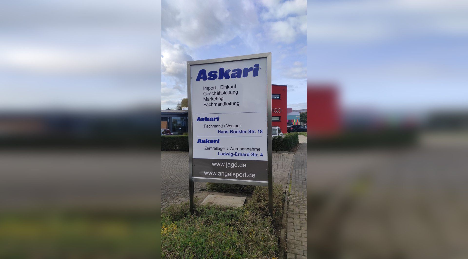 A white sign with the word askari on it is in a parking lot.
