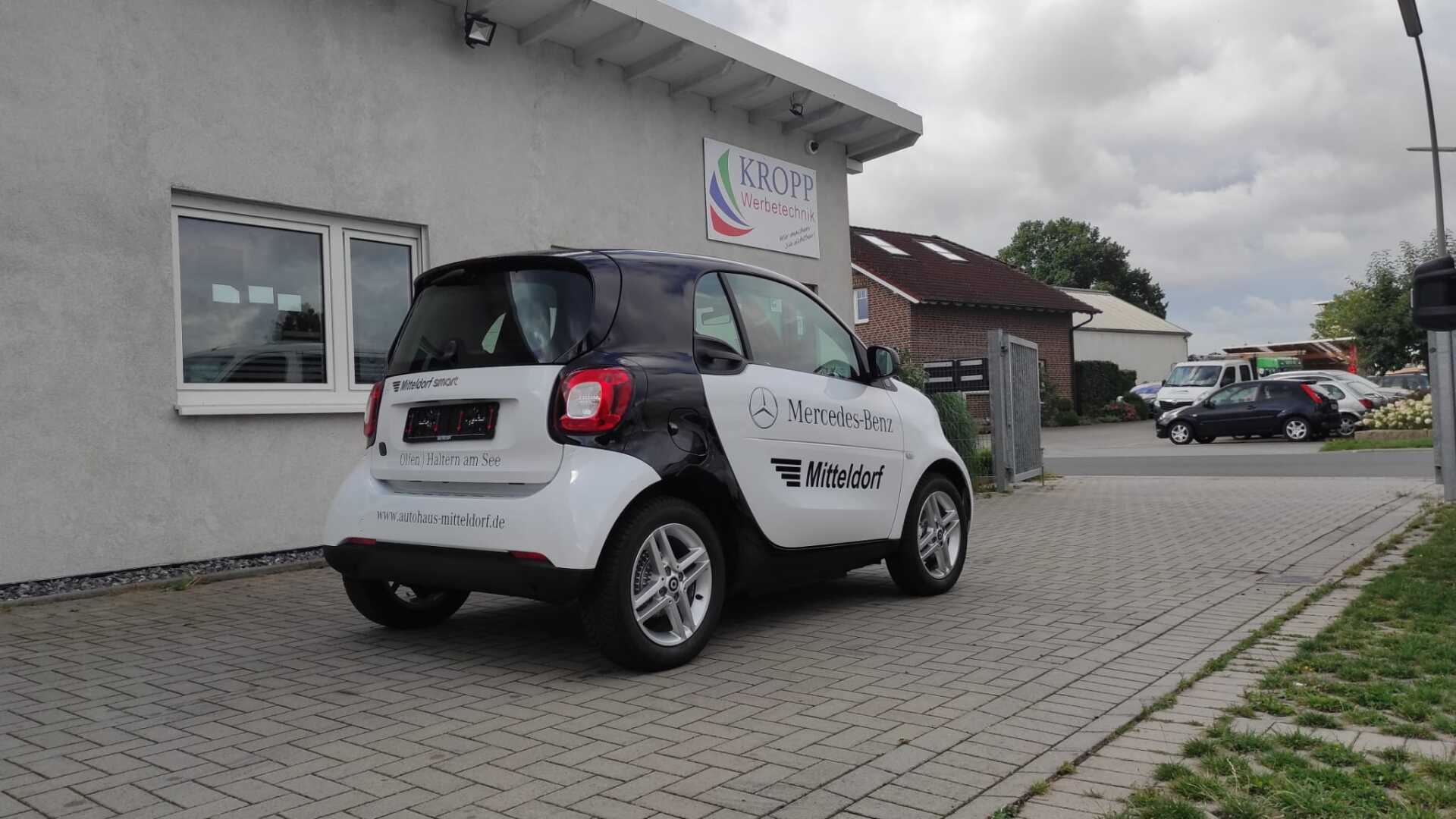 A smart car is parked in front of a building.