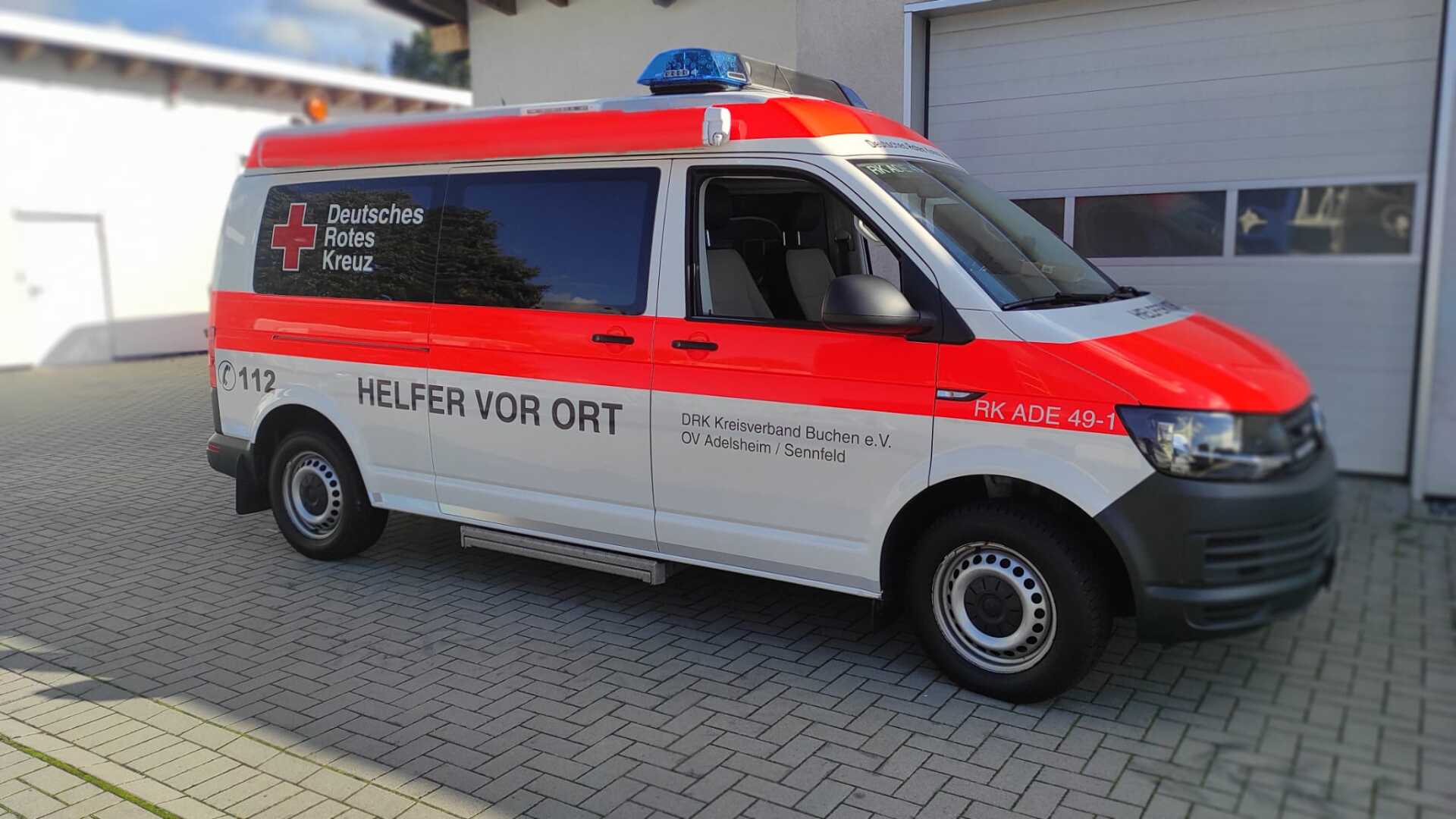 A red and white ambulance is parked in front of a garage.