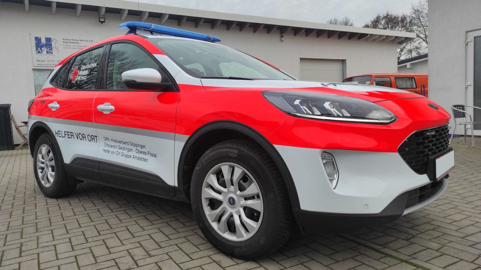 A red and white ford escape is parked in front of a building.