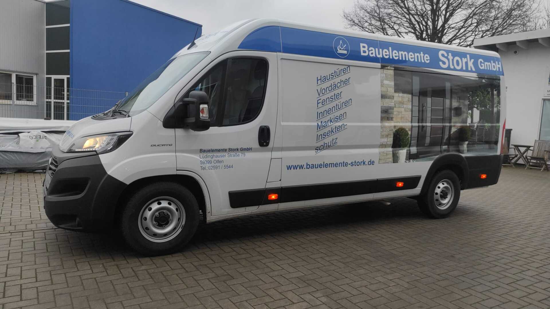 A white van is parked in front of a building.