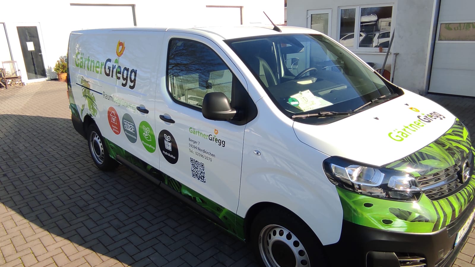 A white van with the word gregg on the side is parked on a brick driveway.