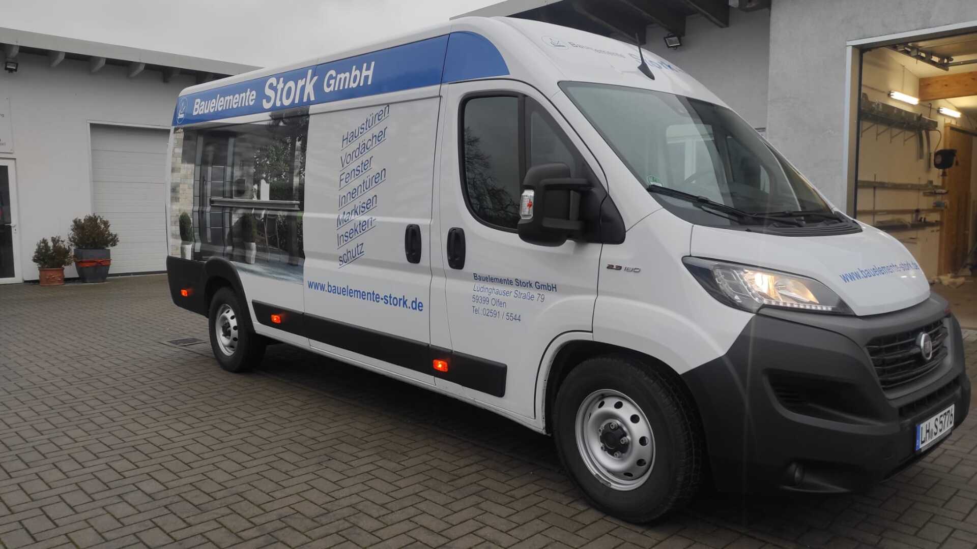 A white van with a blue roof is parked in front of a building.