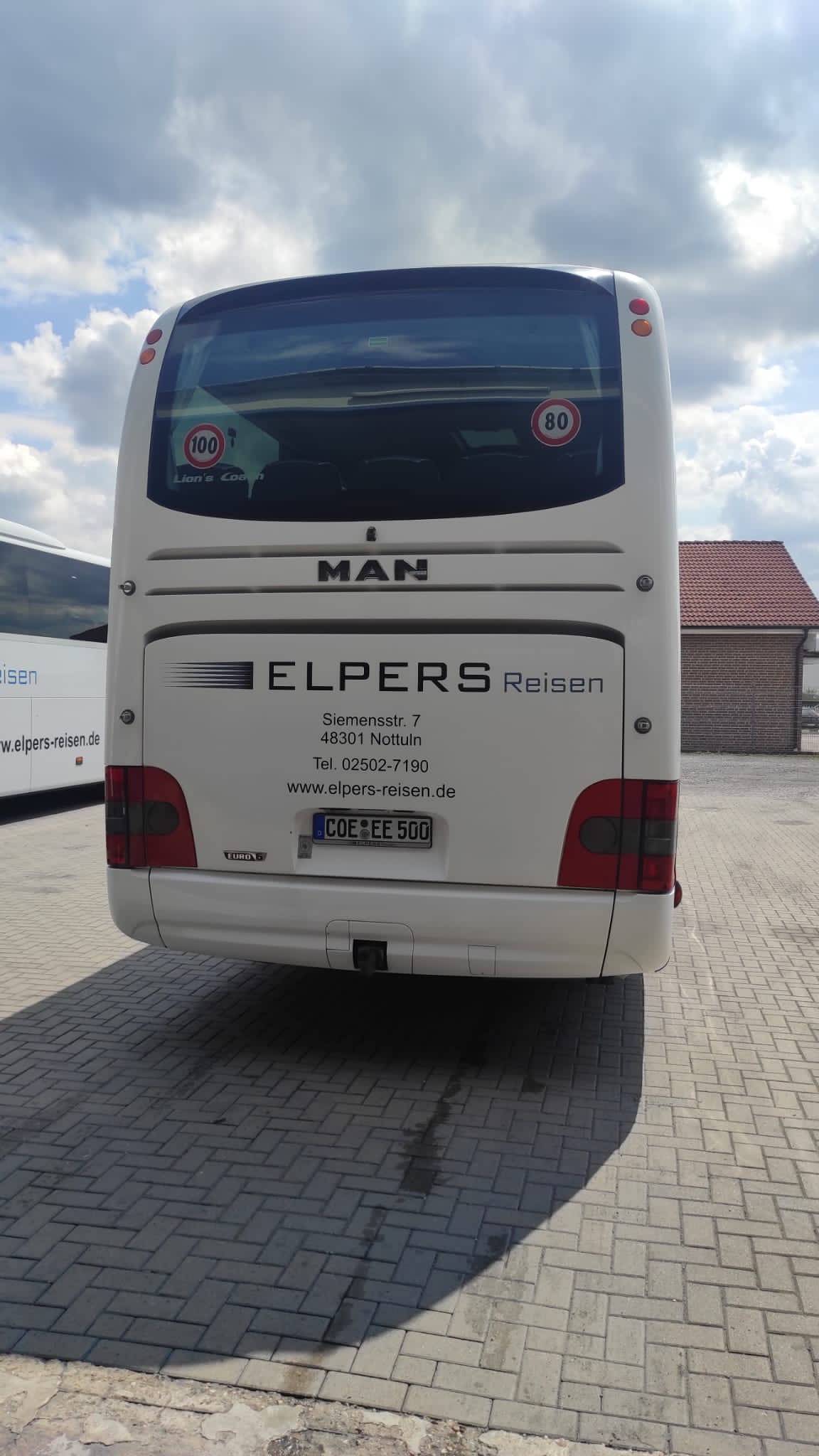 A white man bus is parked in a parking lot.