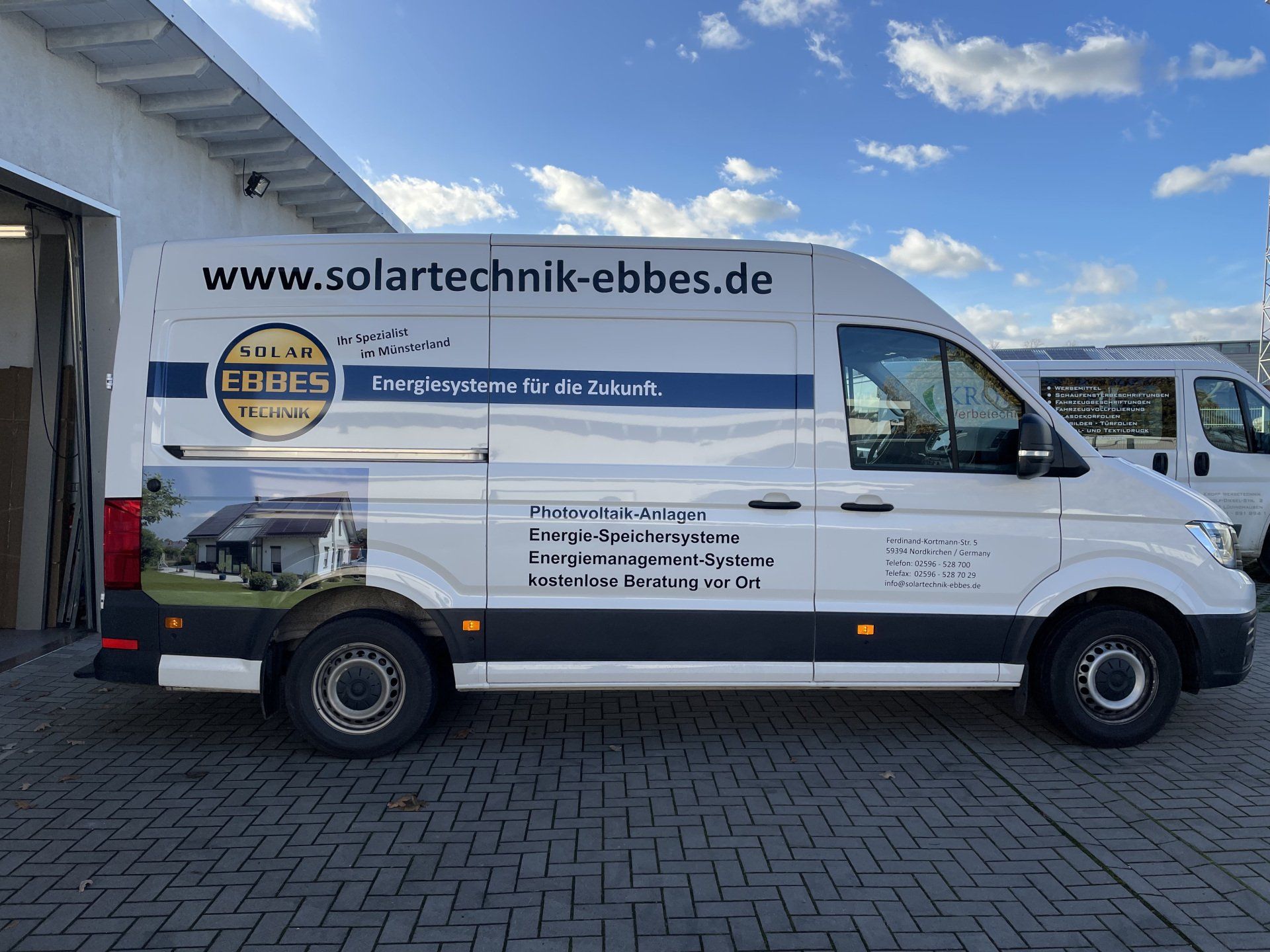 A white van with the website www.solartechnik-ebbes.de on the side is parked in a parking lot.