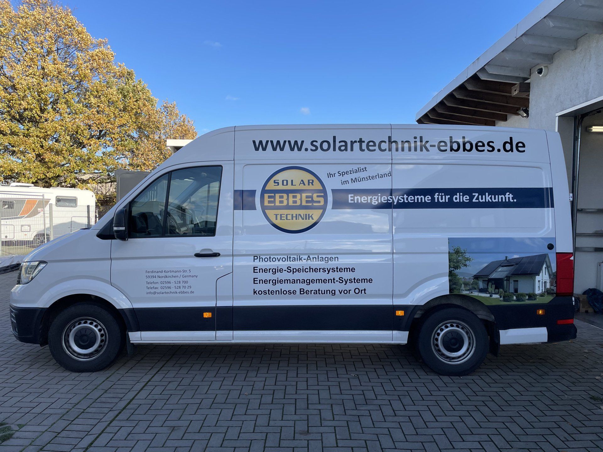 A white van is parked in front of a brick building.