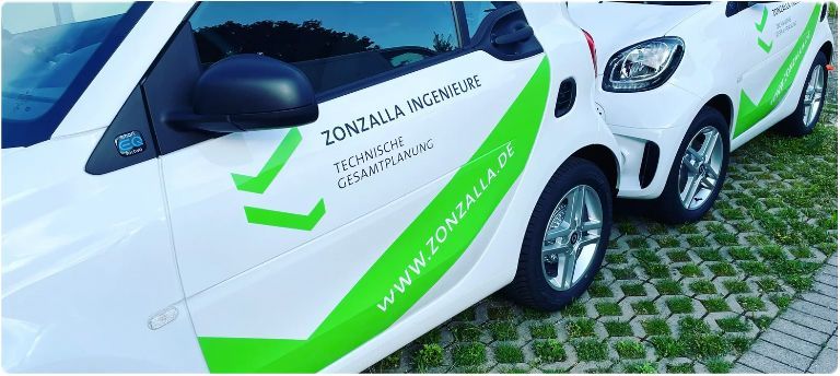 Zwei weiße und grüne Autos stehen nebeneinander