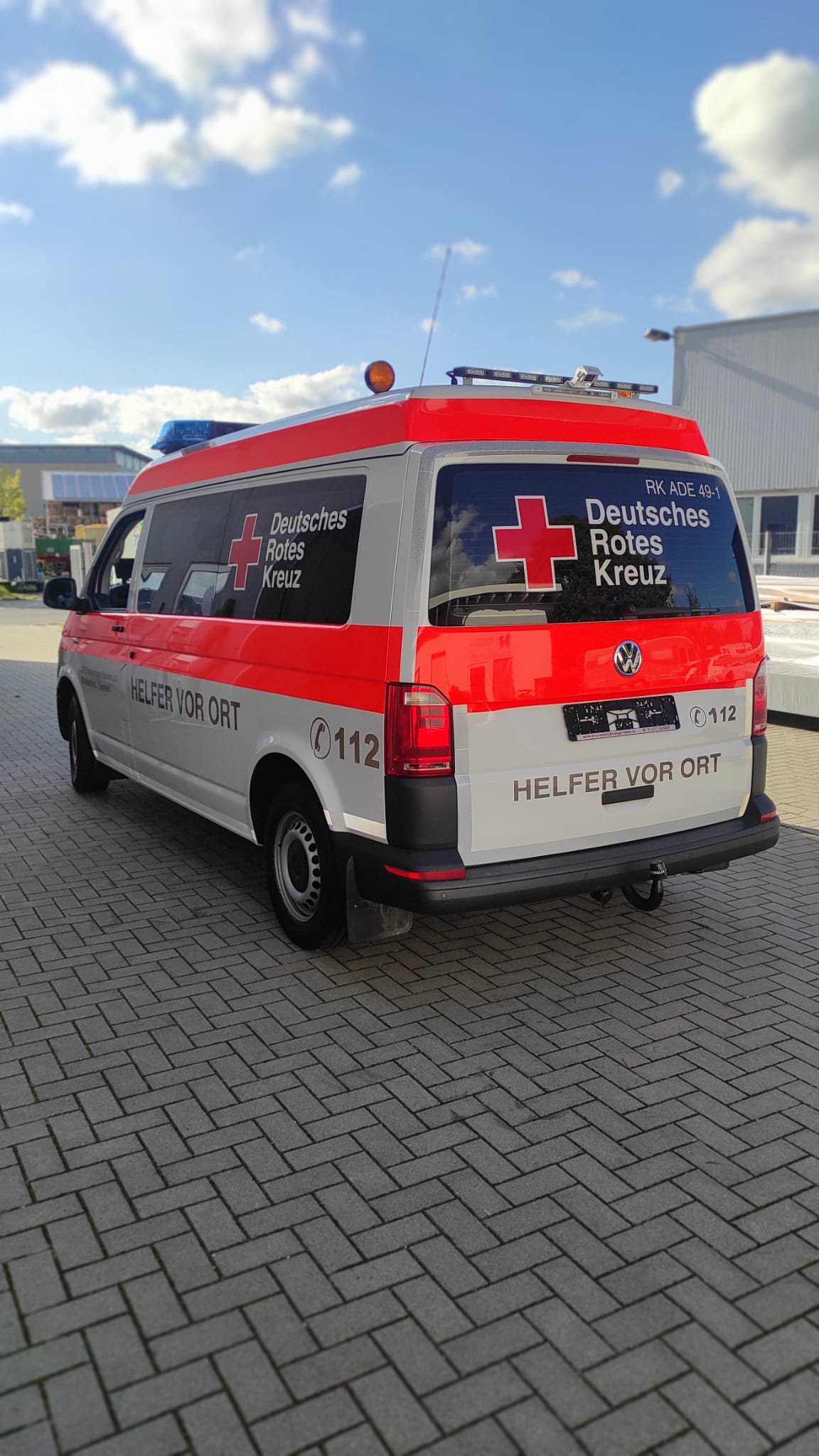 A red and white ambulance is parked on a brick sidewalk.