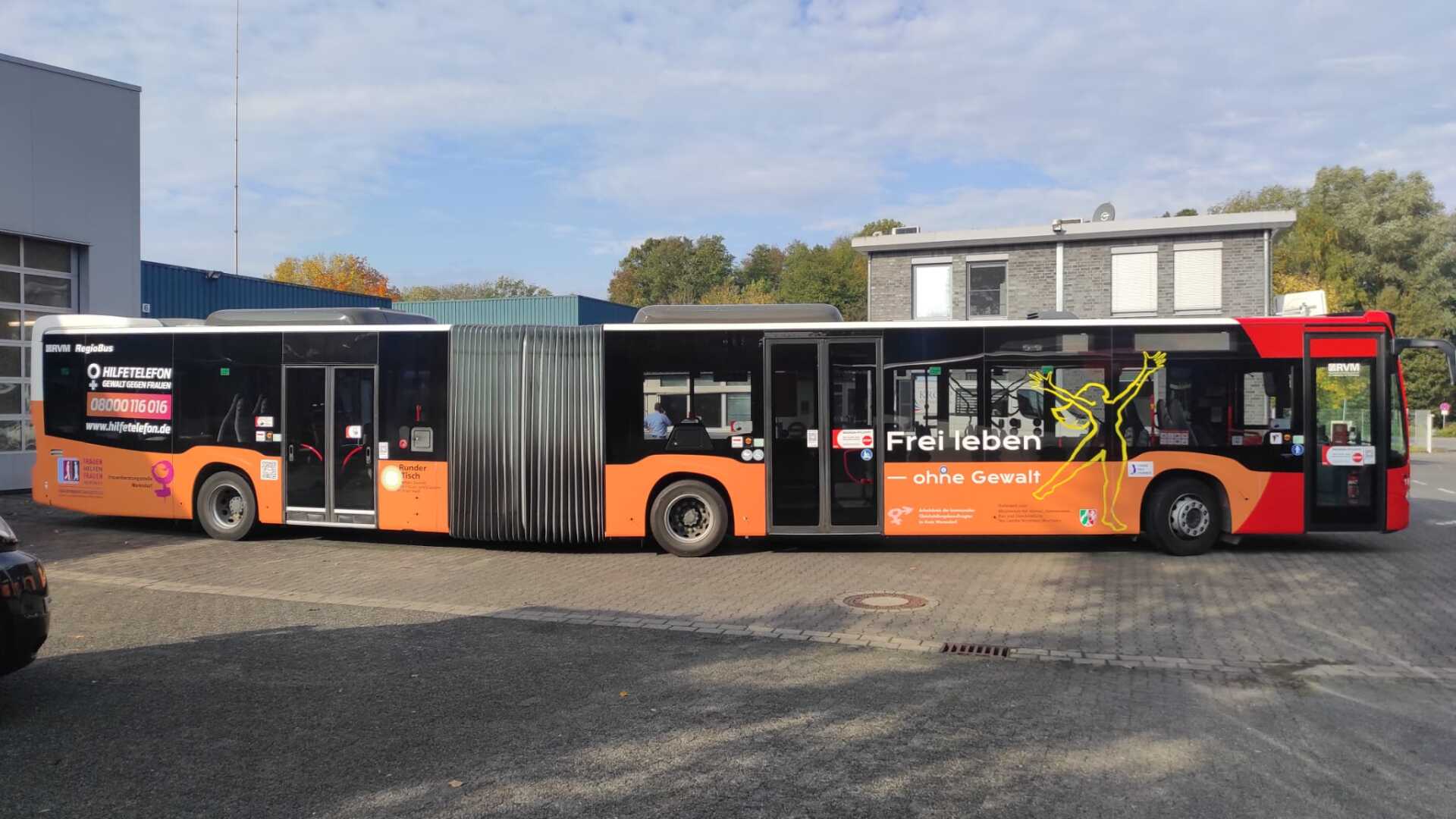 A red and orange bus is parked in a parking lot.