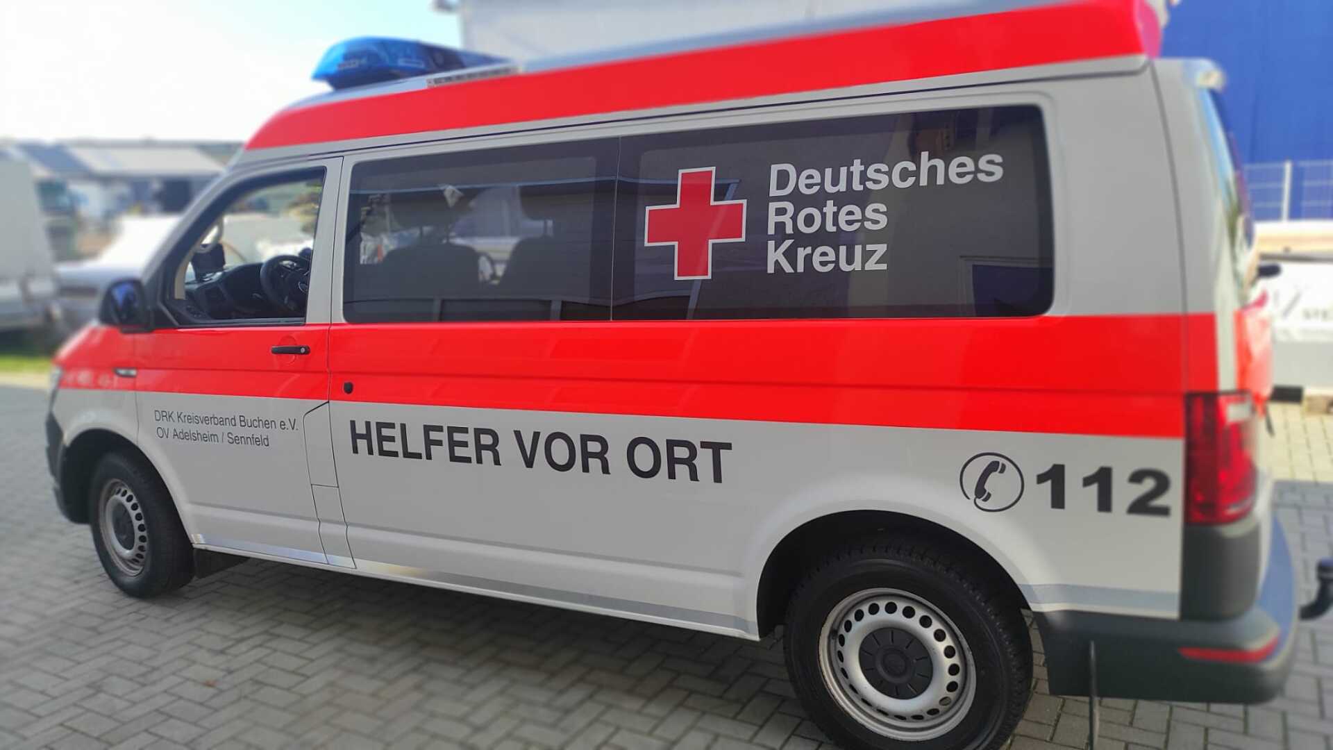 A red and white ambulance is parked in a parking lot.